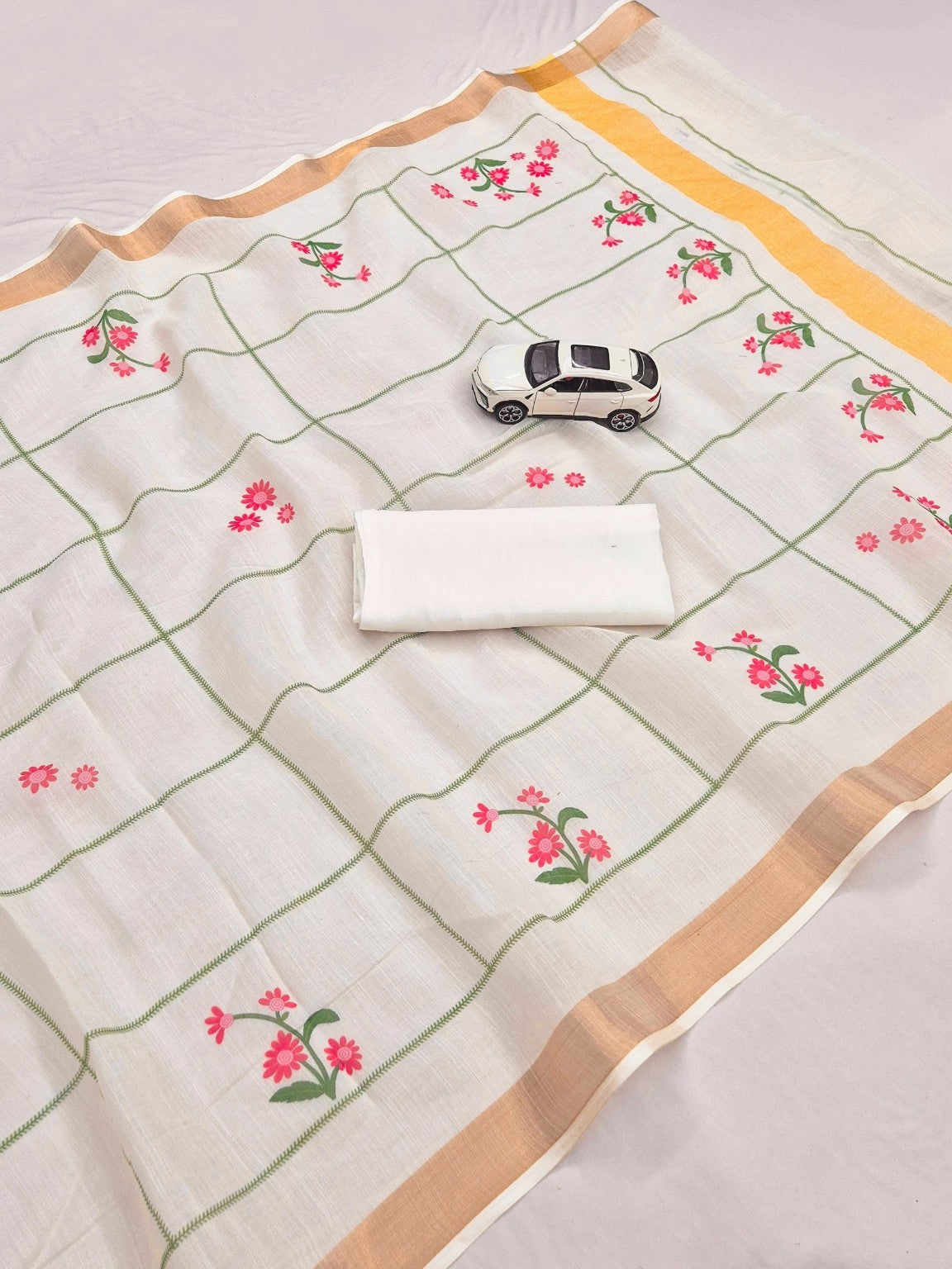 Cream linen saree with pink floral digital print, green grid lines and gold border