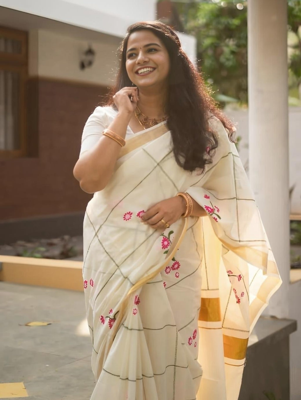 Model wearing cream saree with pink floral prints and gold border