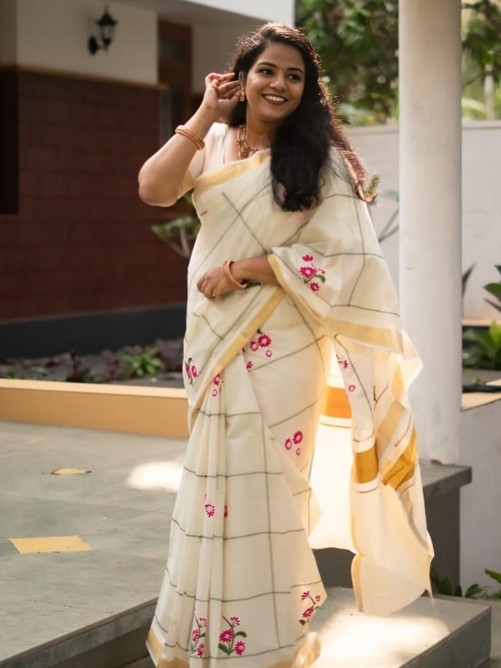 Model wearing cream linen saree with pink floral print and gold border
