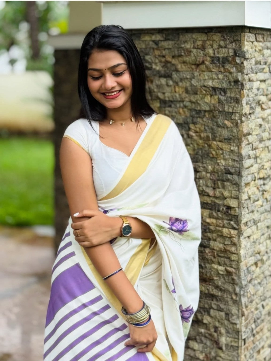 Model wearing white linen saree with purple floral print and gold border